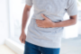 man with stomach pain from IBS holding stomach